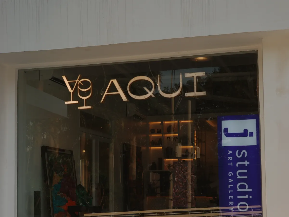 Aqui’s glass front on the second floor: the AQUI logo on the window beside the J Studio sign