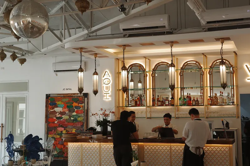 The whole room by day: the bar under its arched mirrors and lanterns, tables and gallery benches in front